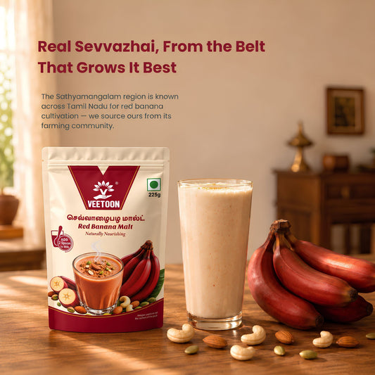 Glass of Red Banana Malt drink with red bananas, cashews and almonds on a table